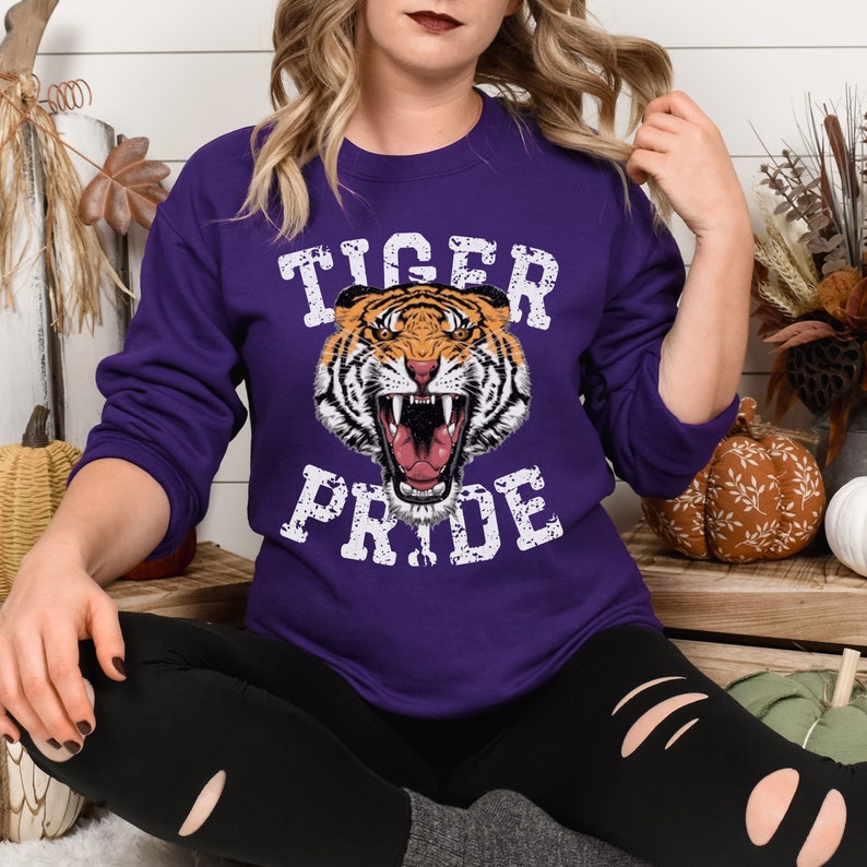 May include: Purple sweatshirt with a white graphic of a tiger with the text "Tiger Pride" in a distressed font.