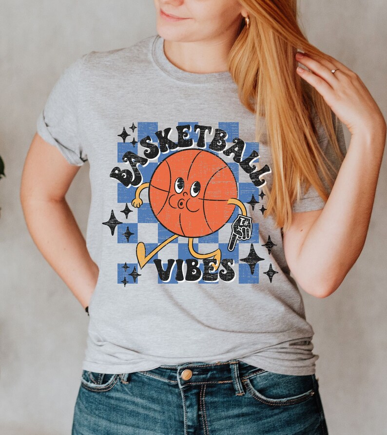 May include: A gray t-shirt with a retro-style basketball graphic. The basketball has a face and is holding a basketball. The text "Basketball Vibes" is printed below the basketball.
