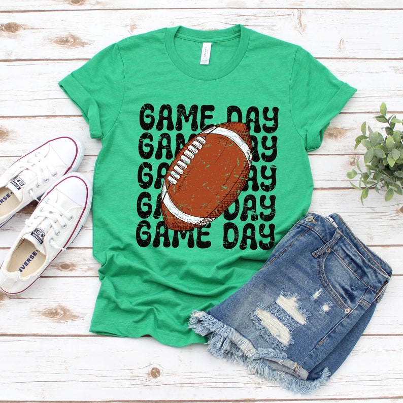 May include: Green t-shirt with a distressed black graphic of a football and the text "GAME DAY" repeated multiple times.