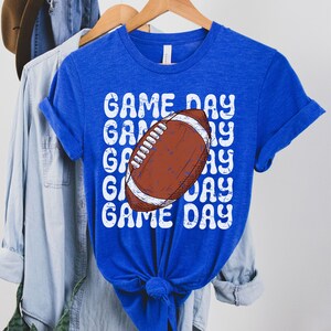 May include: Royal blue t-shirt with a white distressed graphic of a football and the text "GAME DAY" repeated.