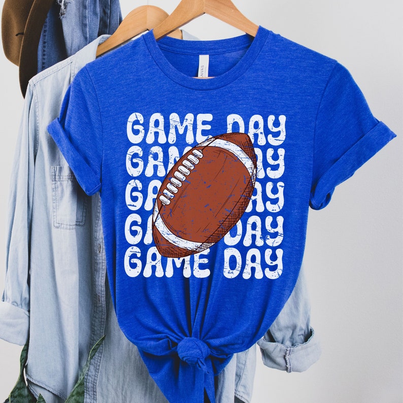 May include: Royal blue t-shirt with a white distressed graphic of a football and the text "GAME DAY" repeated.