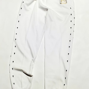 May include: White sweatpants with black diamond-shaped accents down the sides and a gold letter "B" on the right hip.