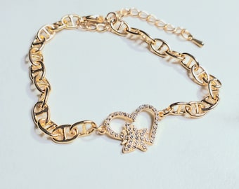 Gold finished link bracelet with cubic zirconia heart and butterfly charm, adjustable length.