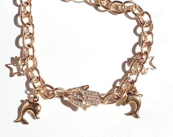 Link chain Bracelet with dolphins, stars, and hamsa/hand cubic zirconia charms. Gold finished fashion jewelry