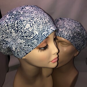 May include: Two surgical caps with a white and blue paisley pattern. The caps are made of a soft, breathable fabric and are designed to be comfortable to wear.