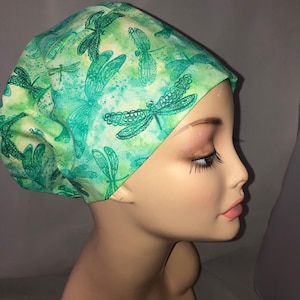 May include: A green and white scrub hat with a dragonfly print. The hat is made of a soft, comfortable fabric and is perfect for nurses, doctors, and other healthcare professionals.