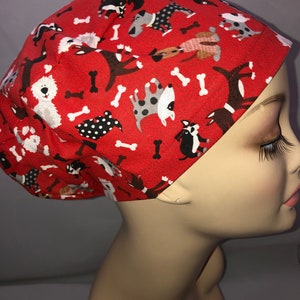 May include: Red scrub hat with a pattern of dogs and bones.
