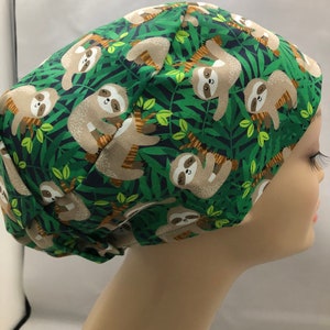 May include: Green scrub hat with a pattern of brown sloths hanging from branches in a jungle setting.