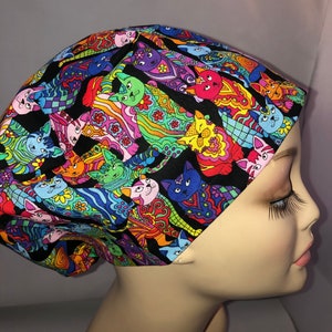 May include: A black scrub hat with a colorful pattern of cats. The cats are drawn in a whimsical style with bright colors and intricate details. The hat is made of a soft, comfortable fabric and is perfect for nurses, doctors, and other healthcare professionals.