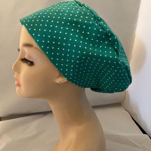 May include: A green scrub hat with white polka dots. The hat is made of a soft, comfortable fabric and is perfect for nurses, doctors, and other healthcare professionals.