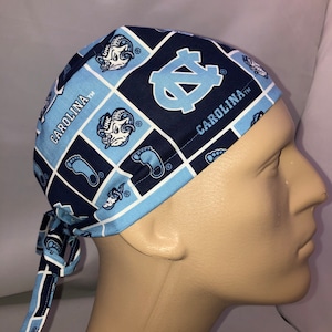 Pu&ograve; includere: Un berretto chirurgico blu e bianco con motivo a fantasia con il logo dei Tar Heels dell'Universit&agrave; della Carolina del Nord e il testo "Carolina TM".