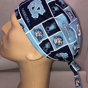 May include: A blue and white patterned surgical scrub hat with the Carolina Tar Heels logo and the text "Carolina TM".