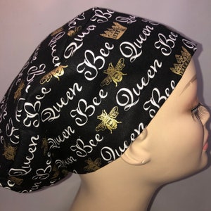 May include: Black scrub hat with a white and gold print of bees and the words "Queen Bee".