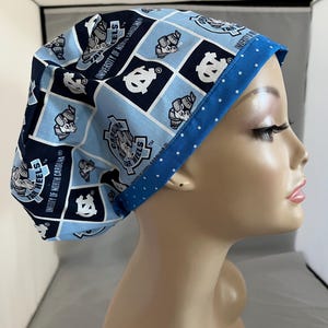 May include: A blue and white patterned surgical scrub hat with a blue polka dot trim. The hat features the University of North Carolina Tar Heels logo and the text "Tar Heels" and "University of North Carolina".