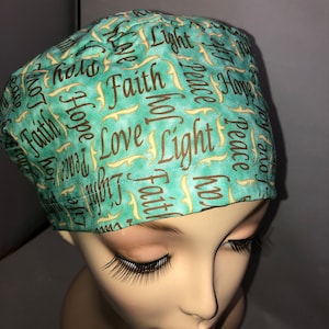 May include: A teal blue scrub hat with a repeating pattern of the words "Faith", "Hope", "Love", "Light", and "Peace" in brown lettering.