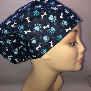 May include: A blue scrub hat with a paw print and bone pattern.