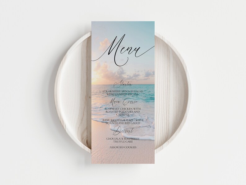 Pu&ograve; includere: Un menu a tema spiaggia con un tramonto sull'oceano come sfondo. Il menu elenca "Antipasto", "Insalata di spinaci e fragole con noci pecan candite", "Piatto principale", "Pollo al rosmarino con patate arrosto e carote", "Ravioli di ricotta al basilico con spinaci e salsa rossa", "Dessert", "Torta al tartufo al cioccolato e lamponi" e "Biscotti assortiti".