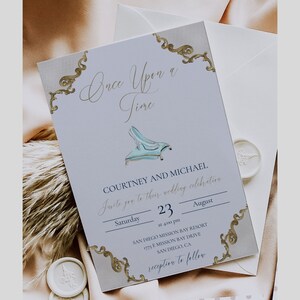 May include: A light blue wedding invitation with gold accents and a Cinderella glass slipper illustration. The invitation reads "Once Upon a Time" and includes the names Courtney and Michael, the date Saturday, August 23, and the time 4:00 pm. The invitation also includes the location of the wedding, San Diego Mission Bay Resort, 1775 E Mission Bay Drive, San Diego, CA. The invitation concludes with "reception to follow".
