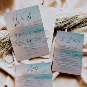 Pu&ograve; includere: Un set di inviti di nozze a tema spiaggia in blu e bianco. L'invito presenta un tramonto sull'oceano con il testo "We do" e i nomi "Michael & Courtney". La carta dei dettagli presenta una scena oceanica simile con il testo "The Details" e informazioni sul ricevimento di nozze. La carta di risposta presenta un tramonto sull'oceano con il testo "Reply" e uno spazio per gli ospiti per rispondere.