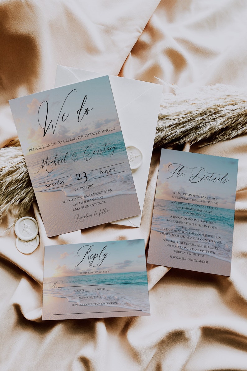 Pu&ograve; includere: Un set di inviti di nozze a tema spiaggia in blu e bianco. L'invito presenta un tramonto sull'oceano con il testo "We do" e i nomi "Michael & Courtney". La carta dei dettagli presenta una scena oceanica simile con il testo "The Details" e informazioni sul ricevimento di nozze. La carta di risposta presenta un tramonto sull'oceano con il testo "Reply" e uno spazio per gli ospiti per rispondere.
