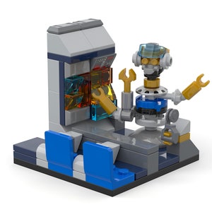 May include: A small, gray, blue, and gold Lego robot with a wrench in its hand stands in front of a Lego control panel with a blue and gray frame. The robot has a clear plastic visor and a gold head. The control panel has a series of clear plastic blocks with gold accents.