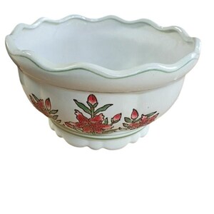 May include: A white ceramic bowl with a scalloped rim and a green painted line along the edge. The exterior features a hand-painted floral pattern with red and pink flowers, green leaves, and buds, set above a scalloped base with a green line.