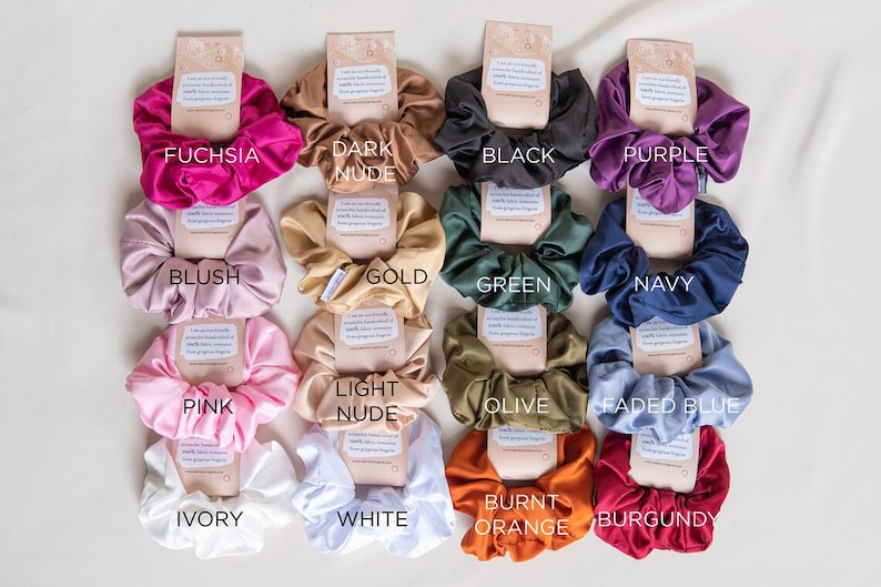 May include: A set of 14 scrunchies in various colors, including fuchsia, dark nude, black, purple, blush, gold, green, navy, pink, light nude, olive, faded blue, burnt orange, and burgundy.