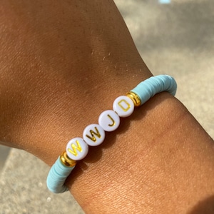 May include: A light blue beaded bracelet with white beads that spell out "WWJD" in gold lettering.