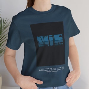 May include: A navy blue t-shirt with a black graphic of a window with a view of a sunset and the word "life" in the window. The text "If you could see your whole life from start to finish, would you change things?" is printed below the graphic.