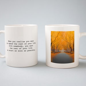 May include: Two white ceramic mugs, one with a quote printed on it and the other with a photo of a path lined with yellow trees. The quote reads: "When you realize you want to spend the rest of your life with somebody, you want the rest of your life to start as soon as possible."