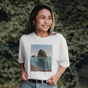 Peut inclure: T-shirt blanc avec un imprimé graphique d'une île verte dans l'océan. Le texte "Never say die." est imprimé sous l'image.