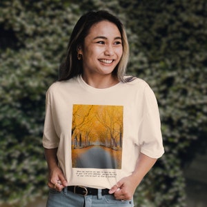 Puede incluir: Una camiseta blanca con un estampado gráfico de un camino bordeado de árboles amarillos. El texto en la camiseta dice: "Cuando te das cuenta de que quieres pasar el resto de tu vida con alguien, quieres que el resto de tu vida comience lo antes posible."