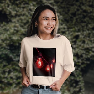 Könnte beinhalten: Ein weißes T-Shirt mit einem Schwarzweißfoto einer Lichterkette mit roten Glühbirnen. Der Text "I won't make a sound" ist unter dem Foto aufgedruckt.