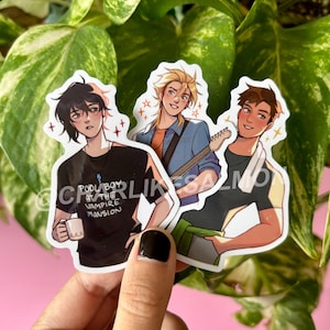 May include: Three stickers featuring anime-style illustrations of male characters. One holds a mug, another a guitar, and the third has a towel around his neck. The stickers have a white border and star accents. Text on one sticker reads "POOL BOY AT THE VAMPIRE MANSION".