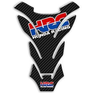 Può includere: Un pad per serbatoio di moto in fibra di carbonio nera con un logo Honda Racing rosso, bianco e blu. Il logo è ripetuto due volte, una volta in alto e una volta in basso sul pad.