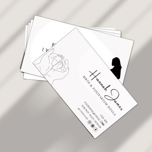 Puede incluir: Tarjeta de visita en blanco y negro con el texto "Hannah James, Birth & Postpartum Doula" e informaci&oacute;n de contacto. La tarjeta tambi&eacute;n presenta un dibujo a l&iacute;nea de manos sosteniendo los pies de un beb&eacute;.