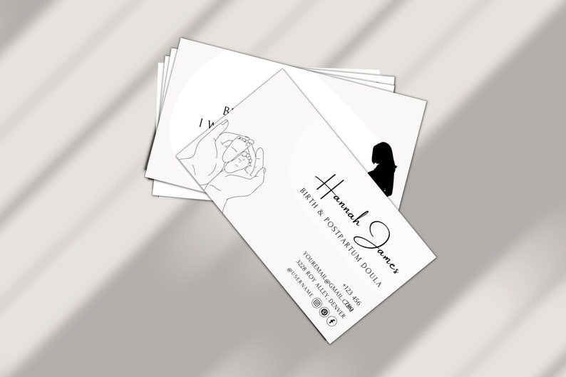 Puede incluir: Tarjeta de visita en blanco y negro con el texto "Hannah James, Birth & Postpartum Doula" e informaci&oacute;n de contacto. La tarjeta tambi&eacute;n presenta un dibujo a l&iacute;nea de manos sosteniendo los pies de un beb&eacute;.