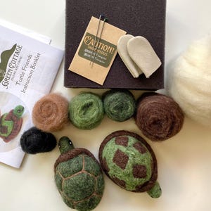 May include: A felt craft kit for making two turtle friends. The kit includes green, brown, and white wool roving, a needle felting tool, and instructions. The kit also includes two finger protectors for needle felting.