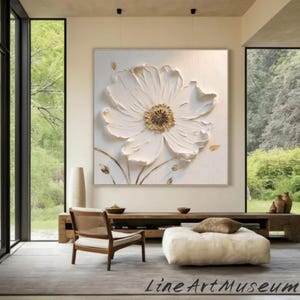 May include: A large, textured white flower painting with a gold center and delicate gold accents. The artwork is displayed in a light-colored room with a wooden bench, chair, and a large window. The text "Line Art Museum" is at the bottom.