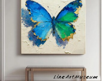 May include: A large, framed painting of a butterfly with blue and green wings, accented with gold. The artwork is set against a textured, off-white background. The painting is displayed above a wooden bench.