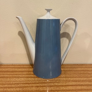 Könnte beinhalten: Eine blaue und weiße Kaffeekanne aus Keramik mit einem weißen Deckel und einem Henkel. Die Kanne hat eine glatte, glänzende Oberfläche.