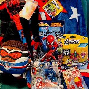 May include: A collection of Marvel Avengers merchandise, including a Spider-Man plush, a Captain America plush, an Avengers blanket, action figures, a coloring book, and lollipops. The blanket is blue with white stars and a red border.