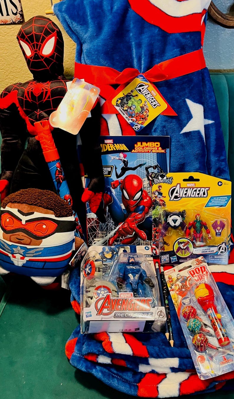 May include: A collection of Marvel Avengers merchandise, including a Spider-Man plush, a Captain America plush, an Avengers blanket, action figures, a coloring book, and lollipops. The blanket is blue with white stars and a red border.