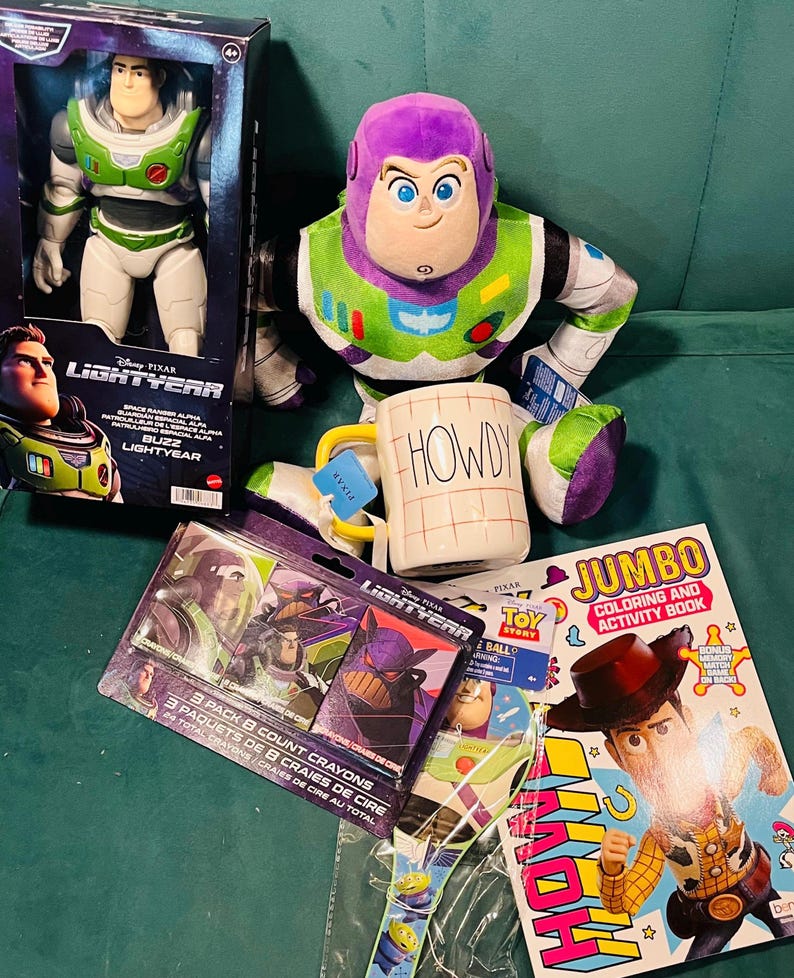 May include: A collection of Toy Story merchandise featuring Buzz Lightyear. Includes a Buzz Lightyear action figure in a box, a plush Buzz Lightyear, a mug with "HOWDY" on it, crayons, a coloring book, and a Toy Story watch.