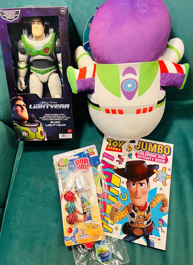 May include: A collection of Toy Story merchandise, including a Buzz Lightyear action figure in a box, a plush Buzz Lightyear, a coloring book, and lollipops. The coloring book features Woody. The items are on a green surface.
