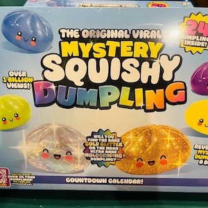 May include: A light blue box for The Original Viral Mystery Squishy Dumpling countdown calendar. The packaging features illustrations of colorful, smiling dumpling toys in blue, purple, green, yellow, holographic, and gold glitter finishes.