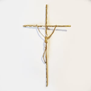 May include: A gold-toned metal crucifix with a stylized figure of a person on the cross.