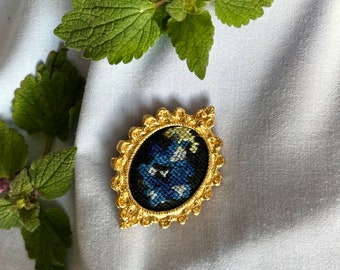 Broche antiguo de metal dorado, camafeo floral azul bordado en punto de cruz.