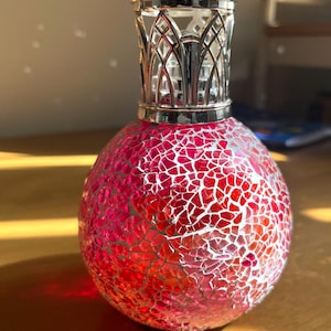 May include: A red and silver mosaic glass diffuser bottle with a decorative metal lid. The bottle is round and has a textured surface.