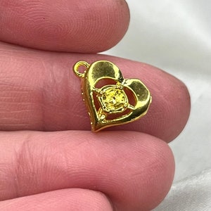 May include: A gold heart-shaped pendant with a clear yellow stone in the centre.